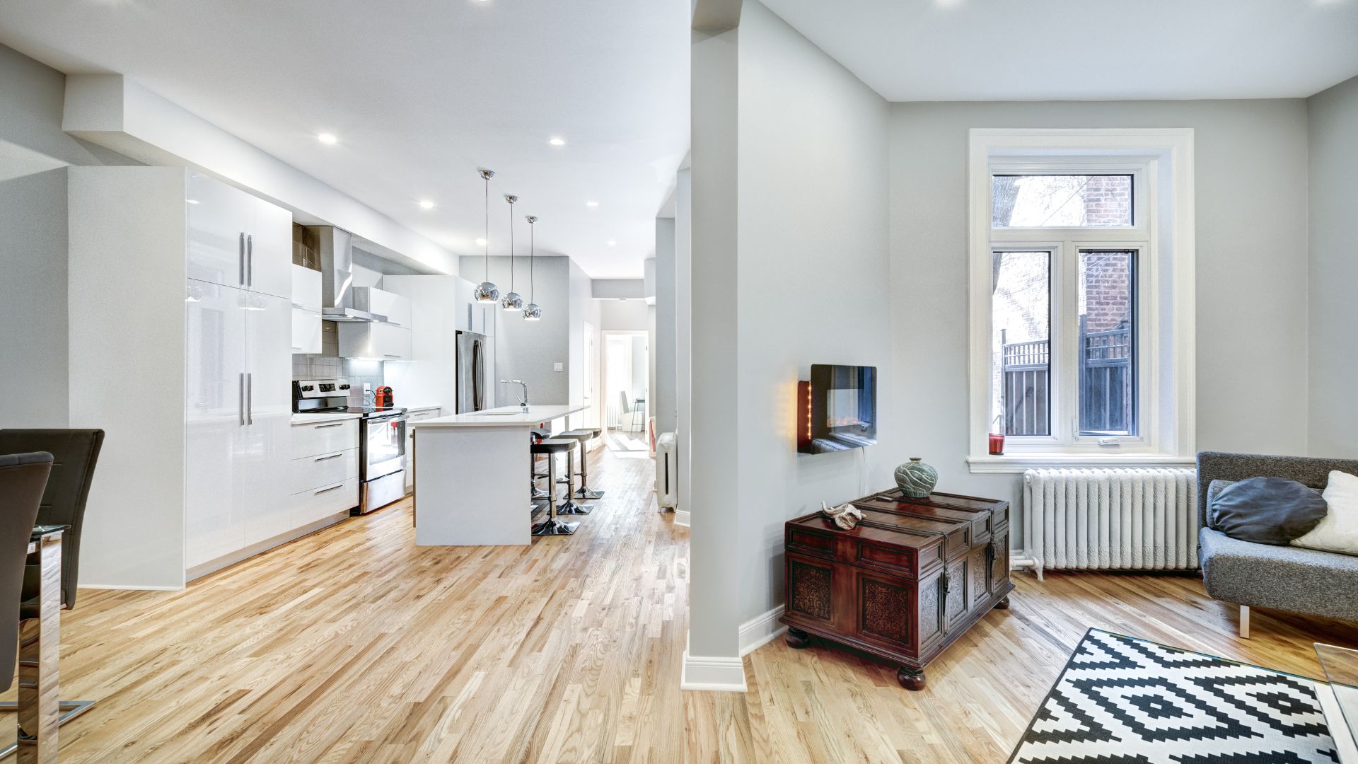Modern open-concept kitchen and living room with white cabinets and wood floor
