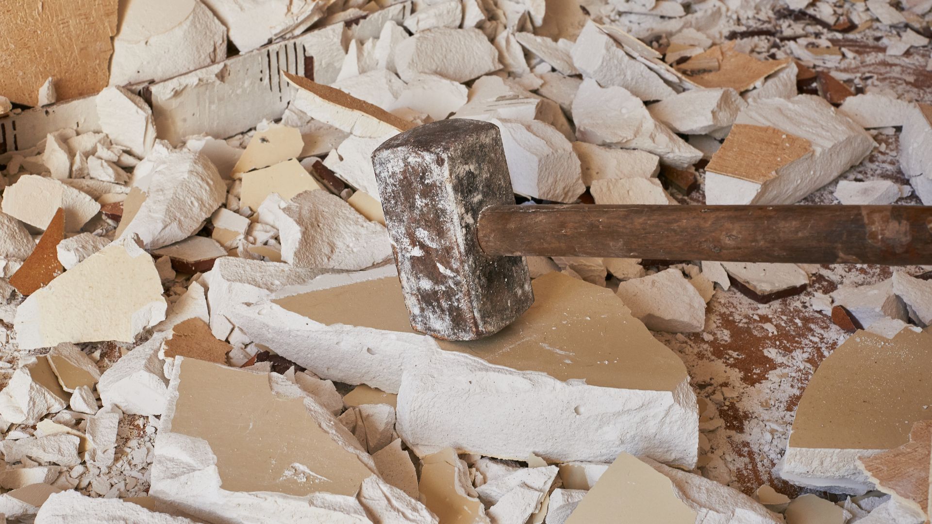 Rusty hammer on broken tiles and construction debris