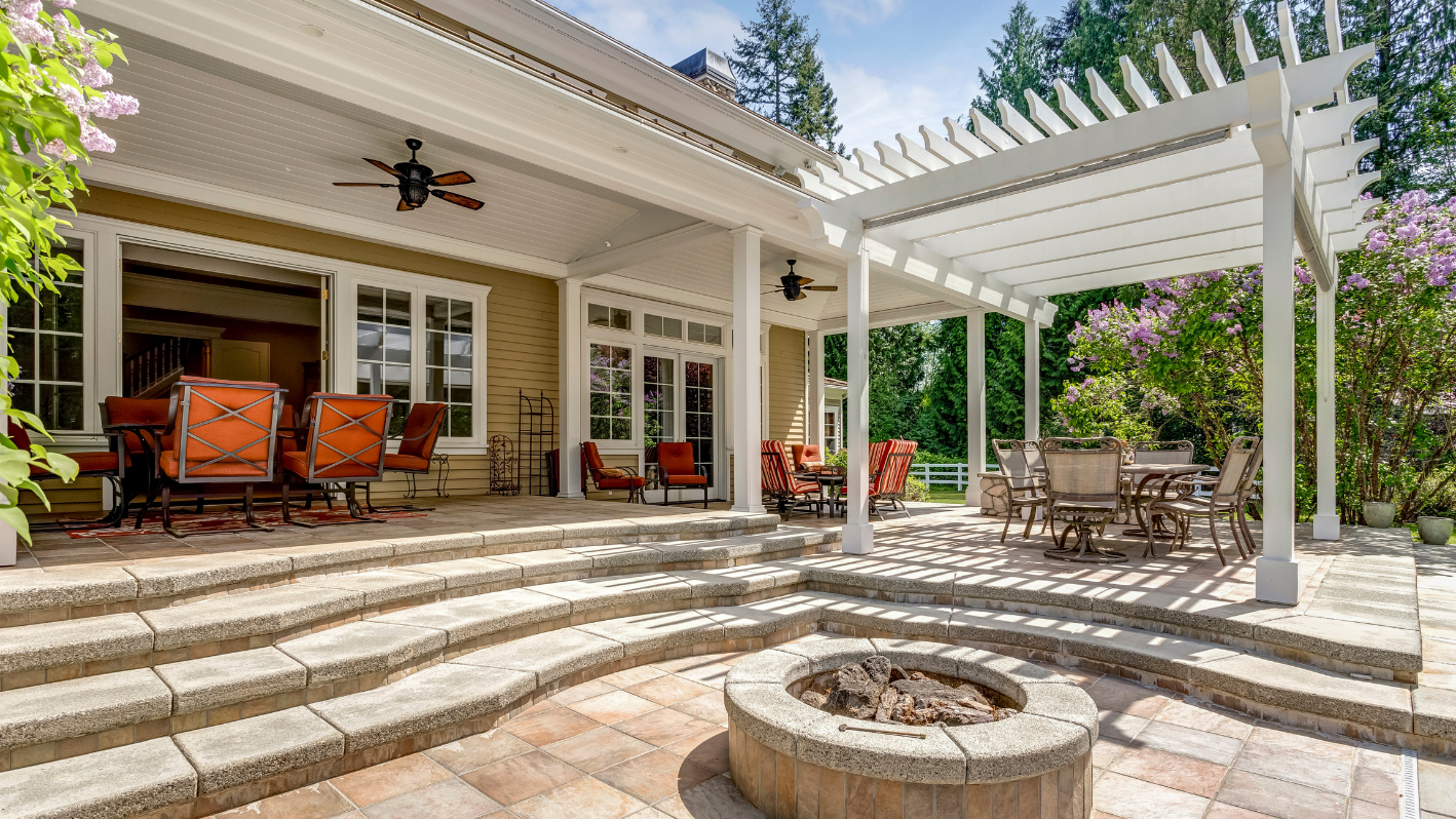 A patio with a fire pit surrounded by chairs